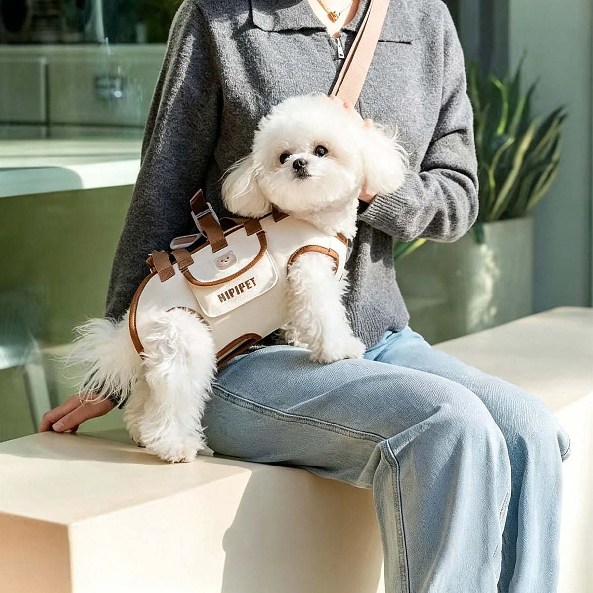 Woman wearing the dog carrier crossbody with a small white dog